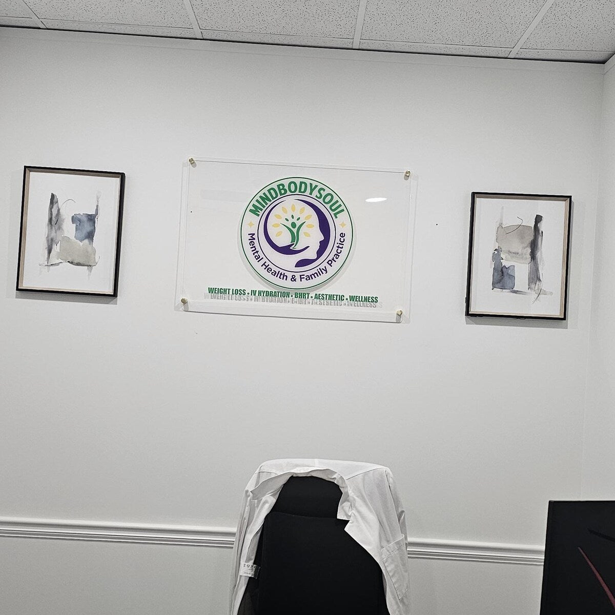 Office wall with a 'MindBodySoul' banner and framed pictures