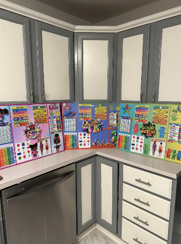 Kitchen corner with gray cabinets, white drawers, and colorful Sour Patch Kids posters on the wall.
